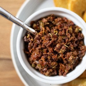 sundried tomato and olive tapenade in a white ramekin with a spoon