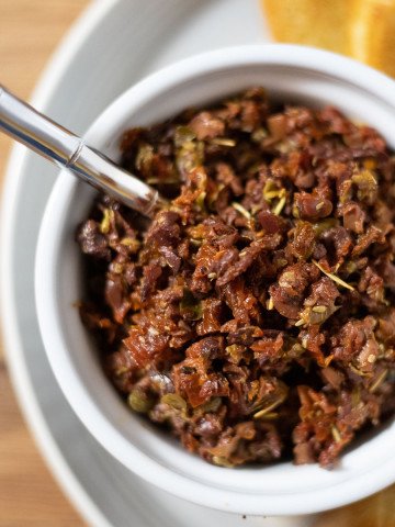 sundried tomato and olive tapenade in a white ramekin with a spoon