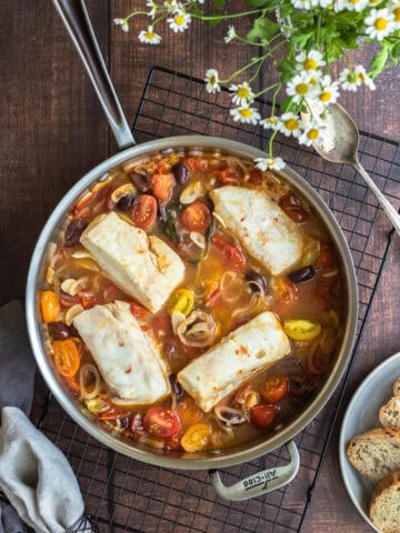 acqua pazza - tomato and garlic poached fish - in a pan on a rack. Bread sits off to the side.