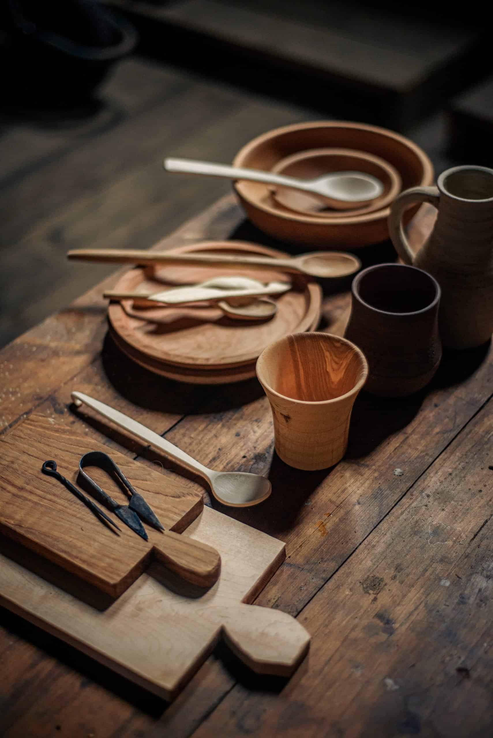 A collection of wood and metal dishes, cutting boards, and cooking implements.
