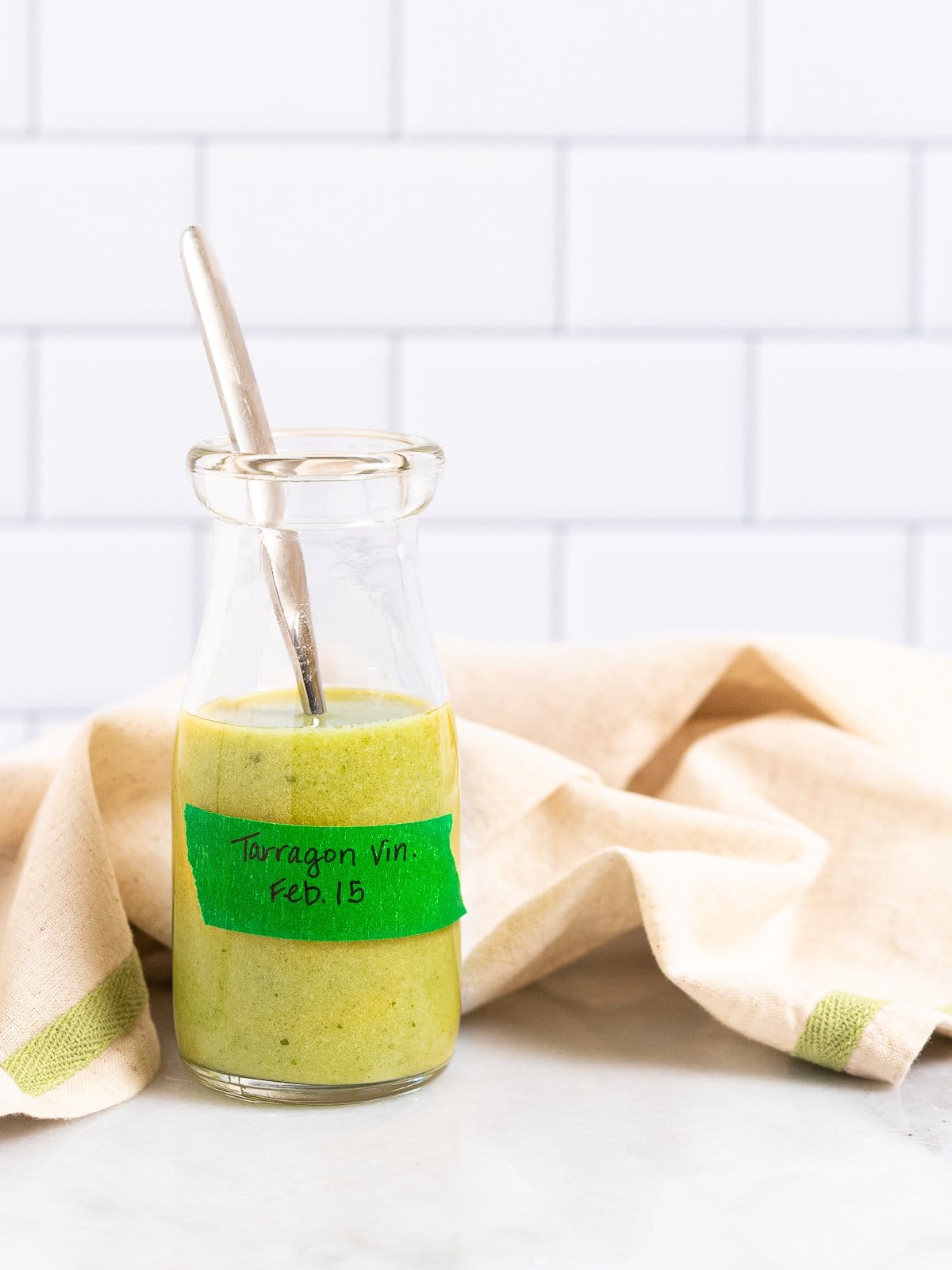 A batch of tarragon vinaigrette in a bottle with a spoon.