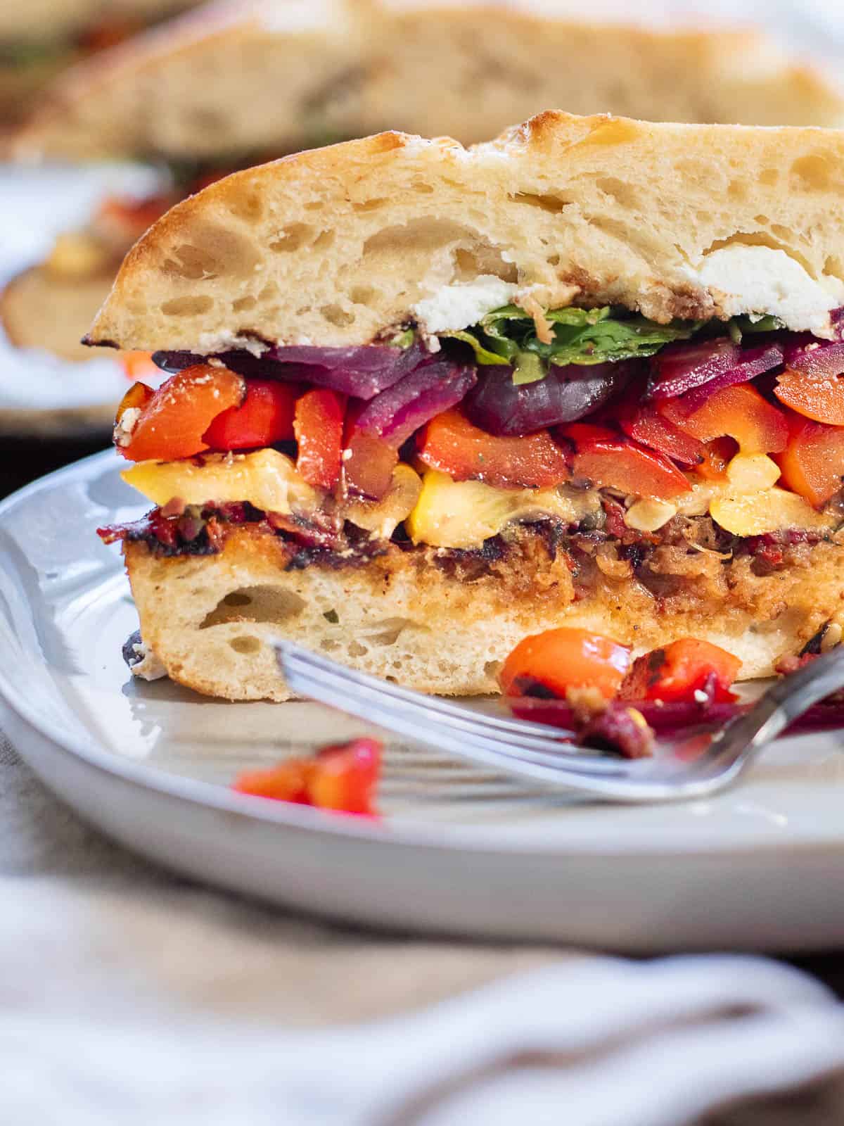 Grilled vegetable sandwich on a plate with a fork.