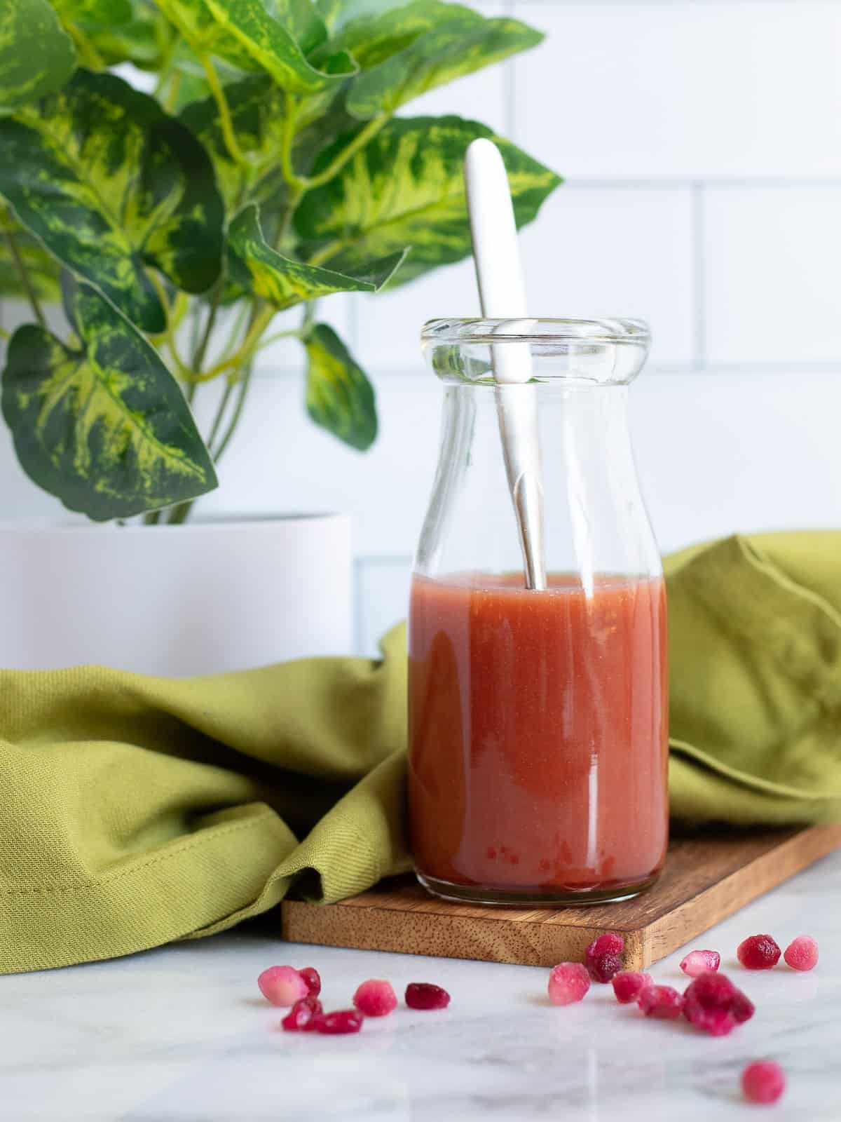 Pomegranate vinaigrette in a jar with a spoon.