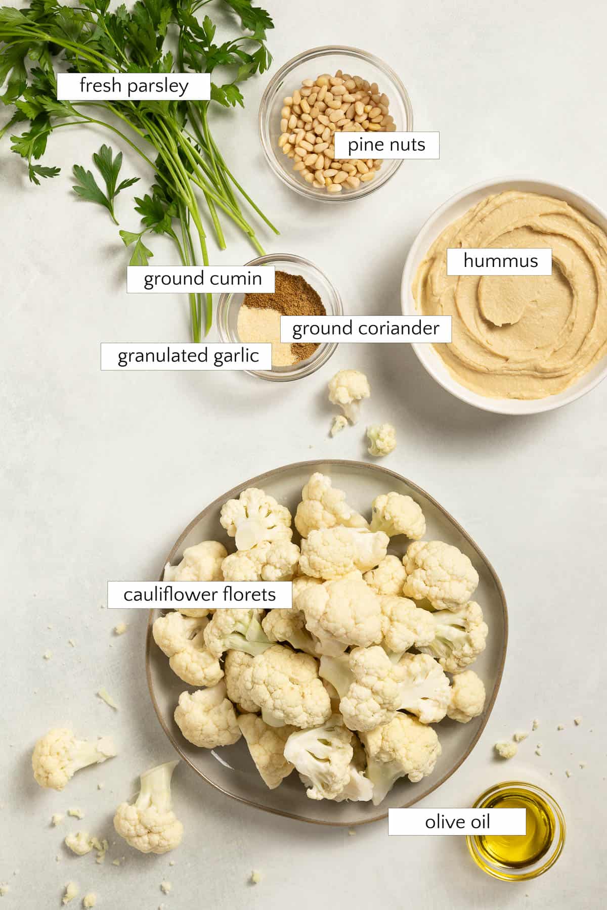 Ingredients for Coriander Roasted Cauliflower: Parsley, hummus, pine nuts, ground cumin, ground coriander, granulated garlic, cauliflower florets, and olive oil.