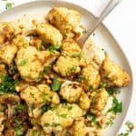 cauliflower coated with coriander, cumin, and garlic and roasted until crispy around the edges. Served over hummus on a shallow platter. Garnished with toasted pine nuts and chopped parsley.