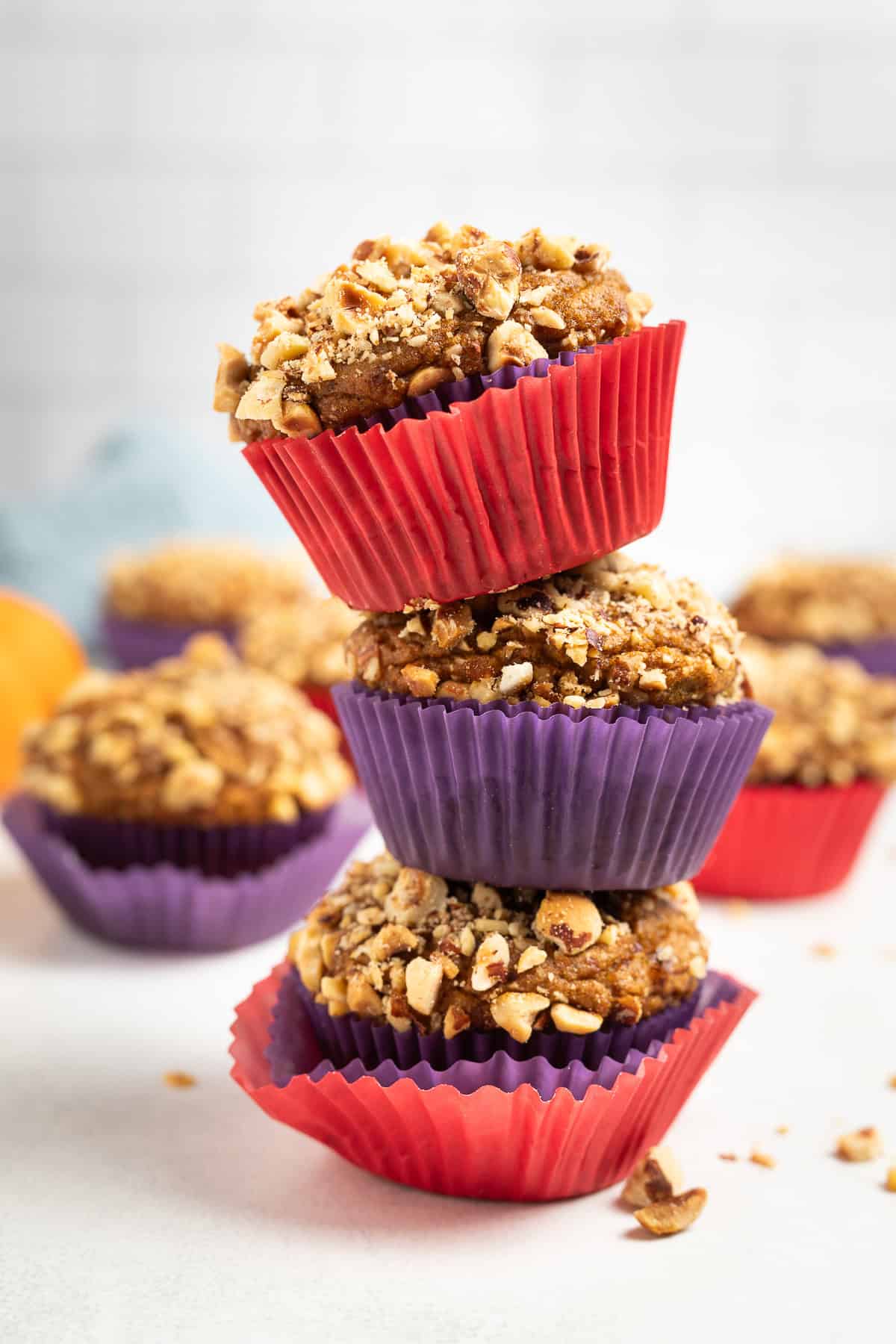 three pumpkin hazelnut muffins stacked with more arranged behind them