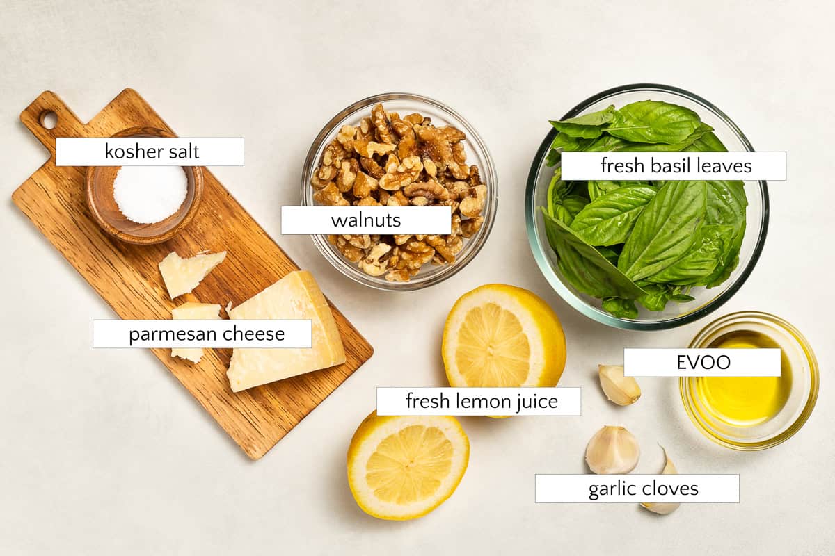 Ingredients for walnut pesto pasta. Fresh basil, walnuts, kosher salt, Parmesan cheese, fresh lemon juice, garlic cloves, and extra virgin olive oil.