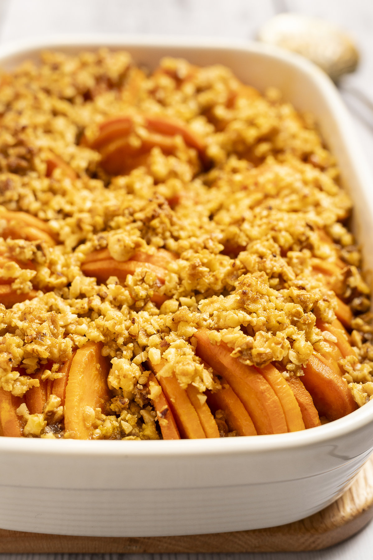 Sweet potatoes are stacked horizontally and topped with nuts and maple sugar in this sweet potato tian with maple nut crumble.