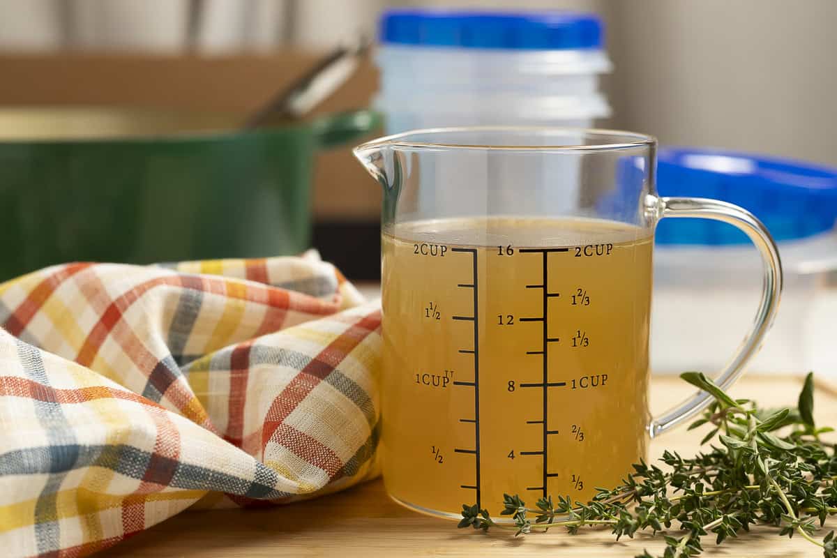 Homemade turkey broth is shown in a measuring cup.