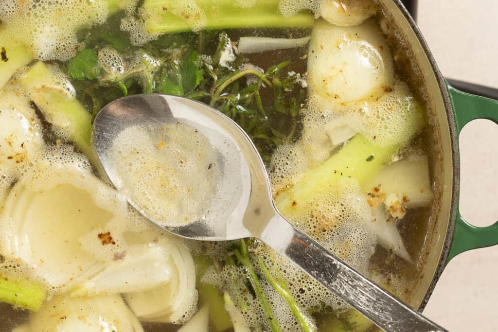 Proteins are skimmed from the top of turkey broth as it comes to a simmer.