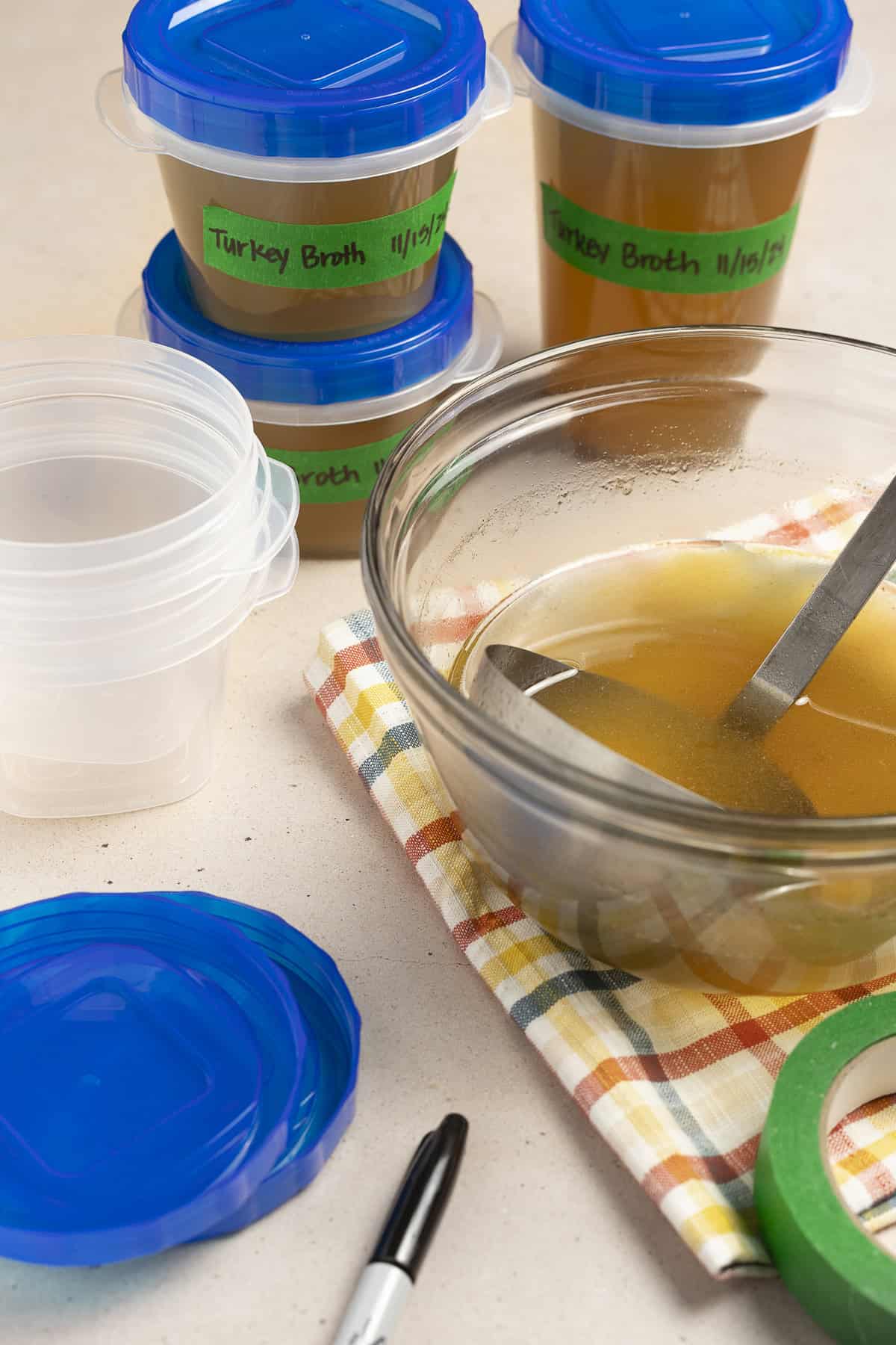 After straining, turkey broth is stored in freezer-safe containers for later use.