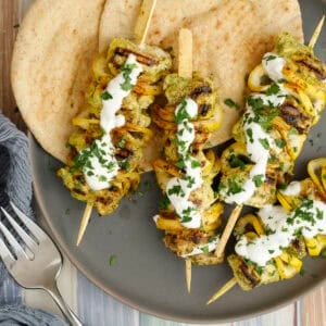 grilled halibut skewers on a platter topped with lemon garlic yogurt sauce and chopped parsley