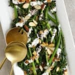 Broccolini on a plate topped with yogurt sauce, almonds, and sumac.