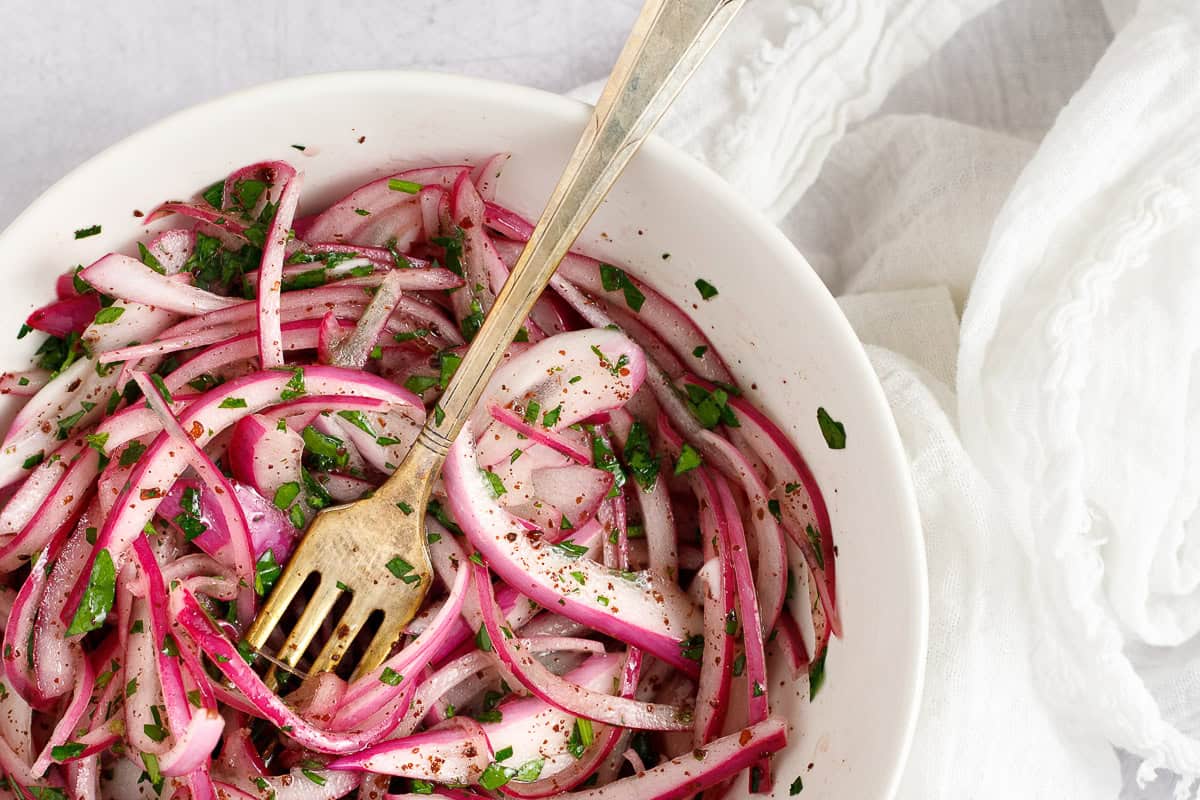 A bowl of sumac pickled onions garnished with parsley.