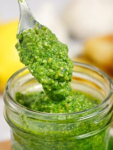 Fresh homemade basil pesto with lemon and almonds in a glass jar. Perfect for pasta, sandwiches, and more.