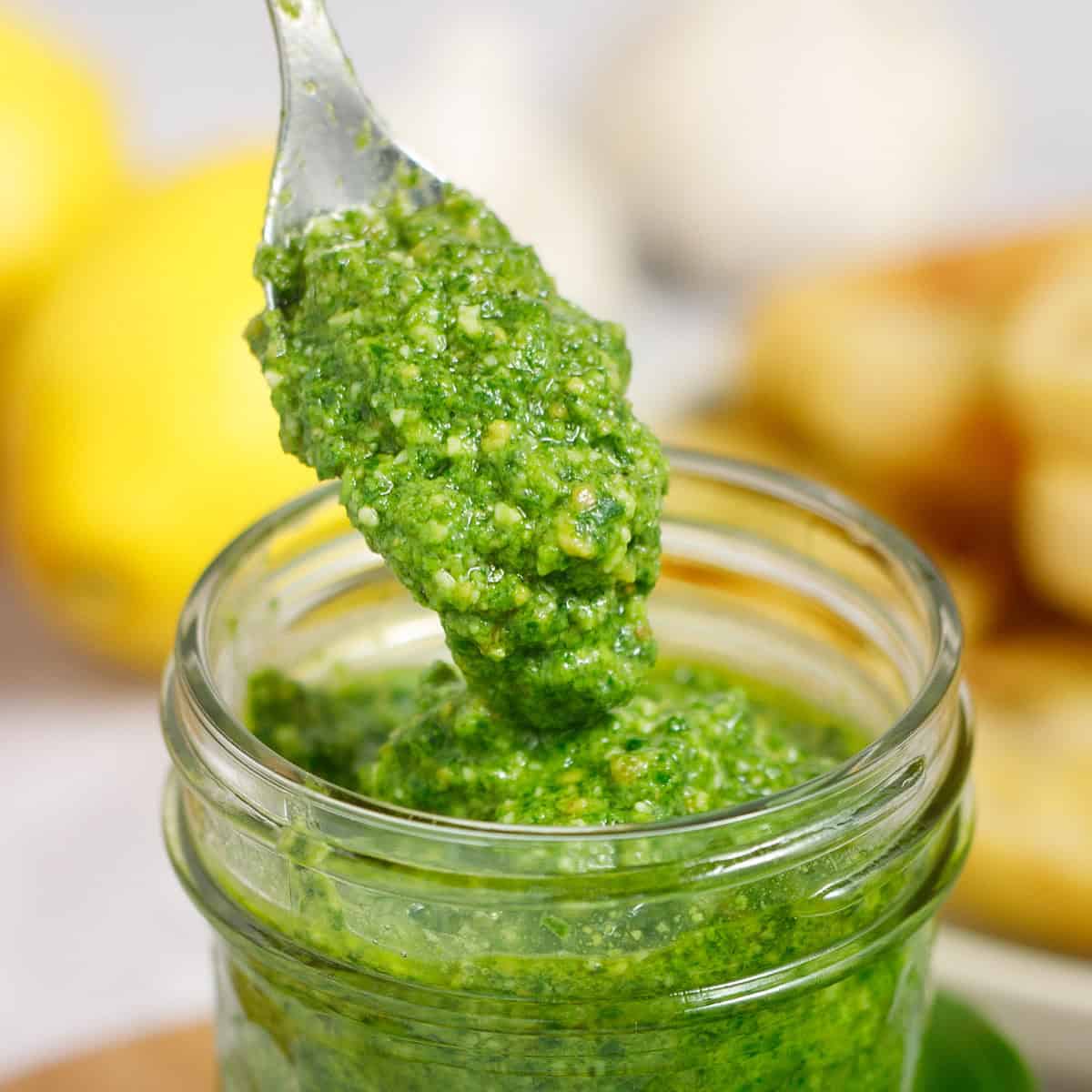 Fresh homemade basil pesto with lemon and almonds in a glass jar. Perfect for pasta, sandwiches, and more.