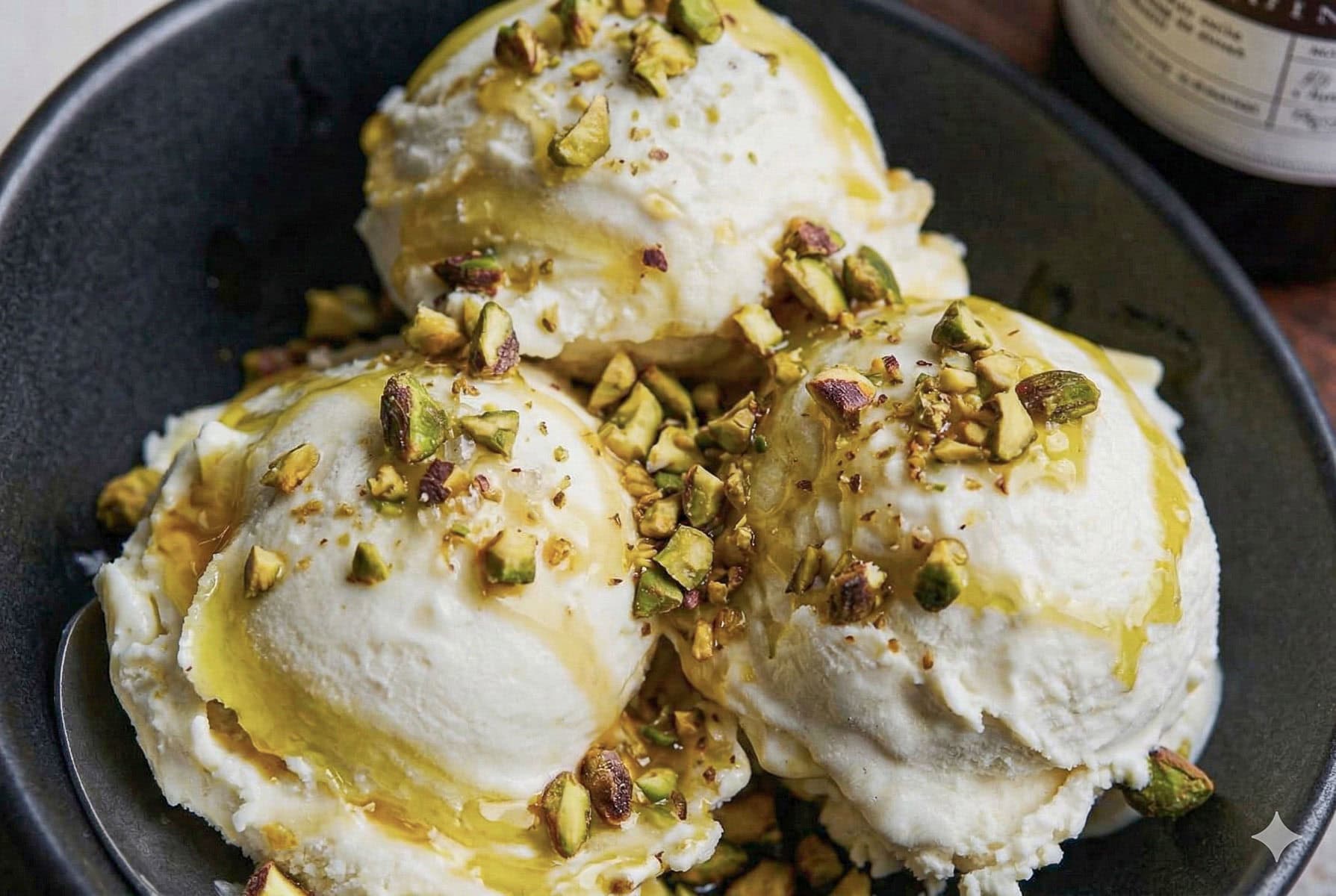 a bowl of ice cream topped with pistachios and olive oil