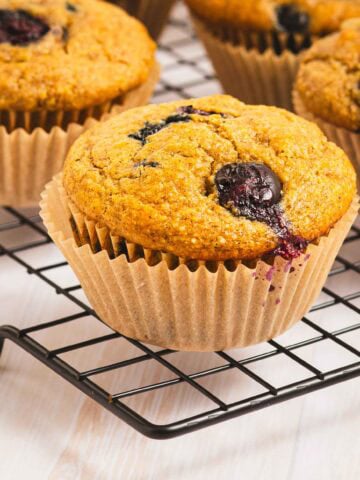 whole grain banana blueberry muffins on a wire cooling rack.