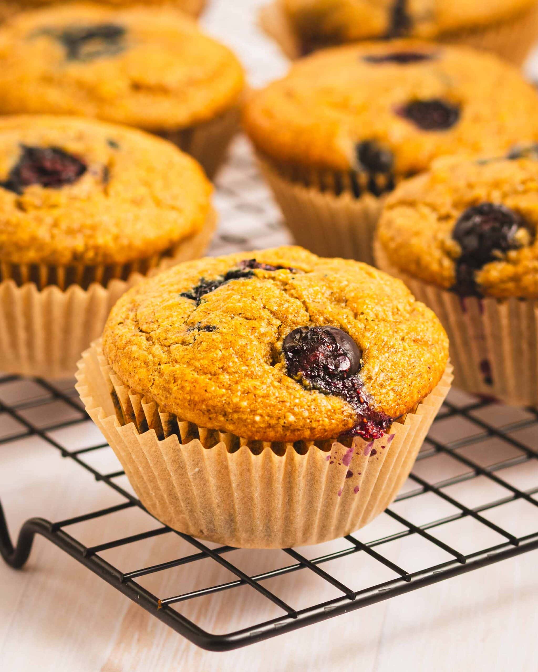 whole grain banana blueberry muffins on a wire cooling rack.