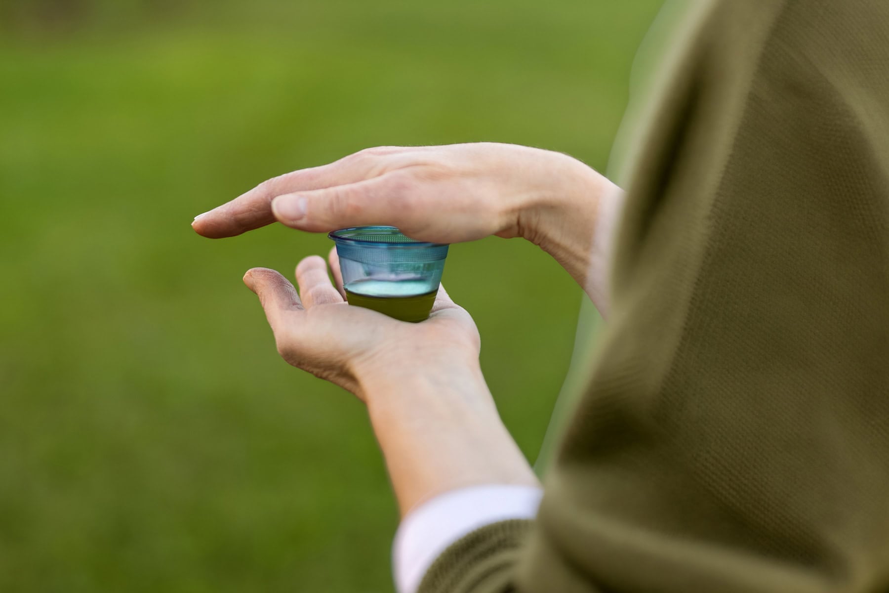 A woman holds a small cup of olive oil in her hands.