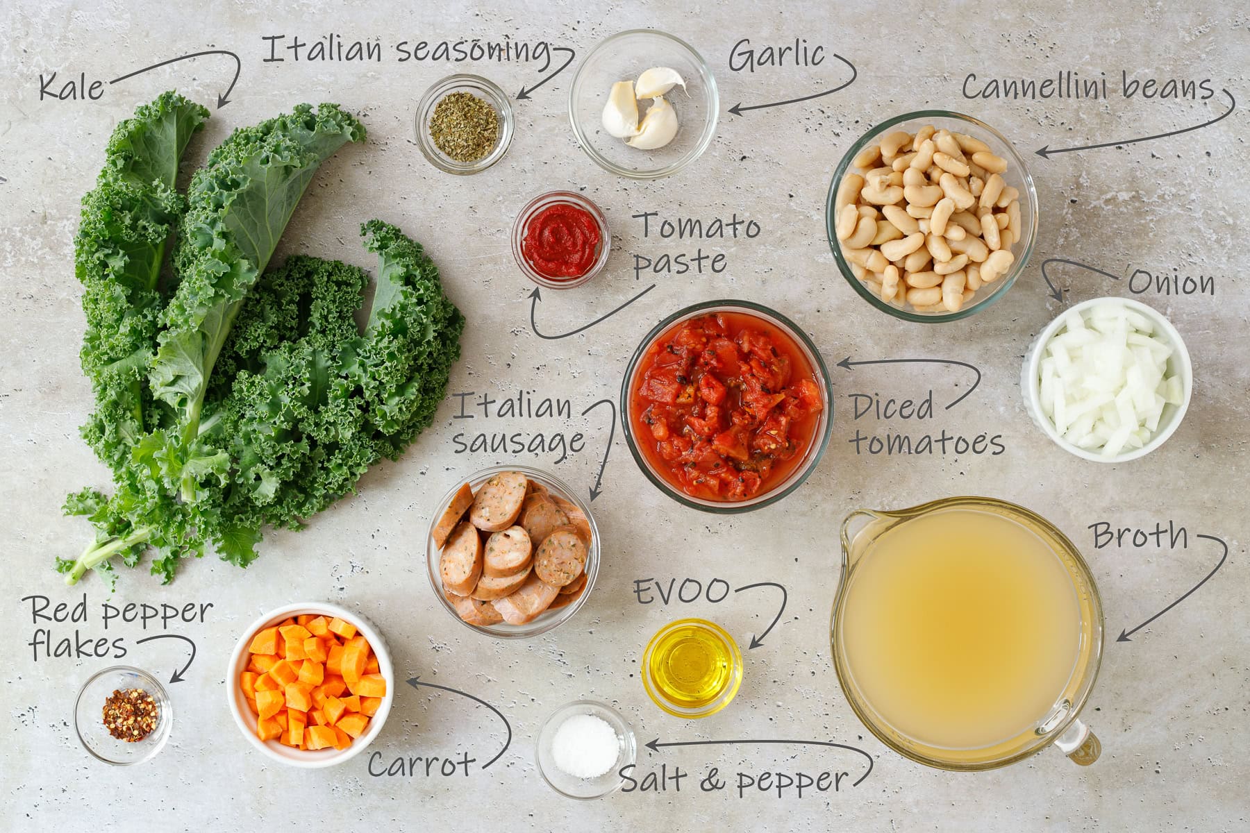 Ingredients for Italian sausage and kale soup - kale, onion, garlic, italian seasoning, Italian sausage, olive oil, carrot, red pepper flakes, salt and pepper, broth, tomato paste, and canned diced tomatoes.